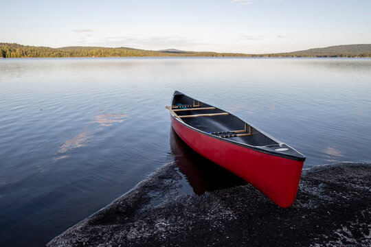 Red canoe on rocky shore of pristine Bald Mountain Pond, Maine