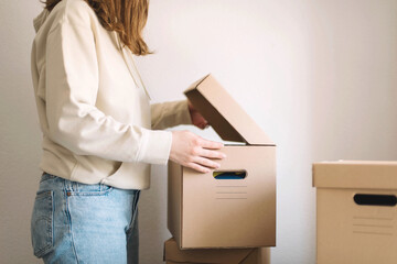 Young  woman moving cardboard boxes in new home