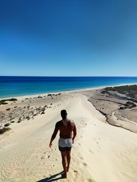 Black man walking down a dune on sotavento beach, Fuerteventura
