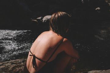Waterdrops glisten on Woman's Tan Back next to a pool.
