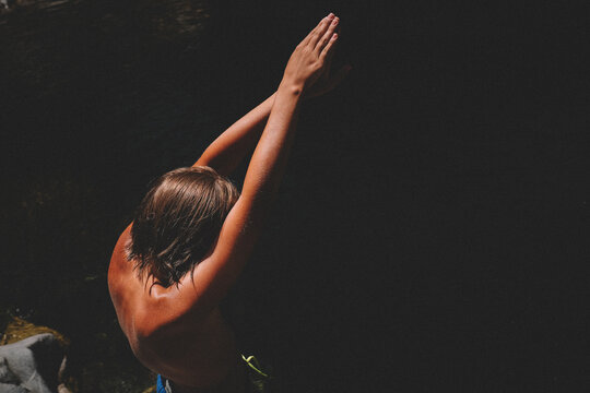 Boy with Tan Skin Prepares to Dive into the Black Water Below