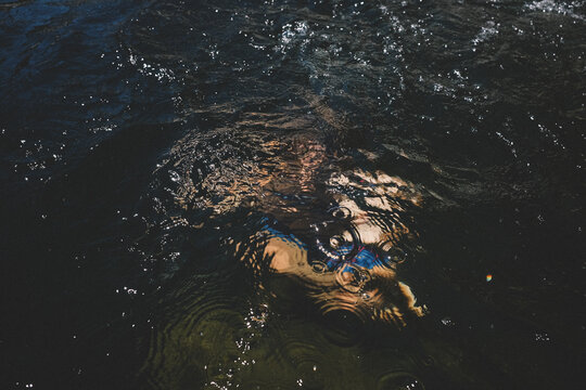 Blurred Figure Under the Surface with Ripples and Bubbles