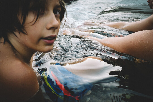 Tween Boy Relaxes in a Pool of Water at Dusk