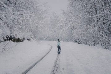 woman walking over snowy road in the forest