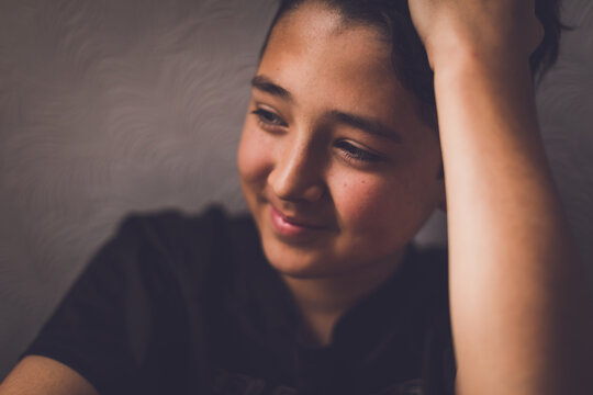 Boy leaning against the wall looking a window.