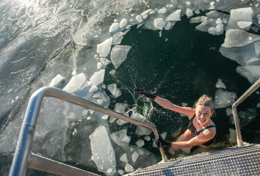 Smiling Woman Making Splash With Icebergs Before Swimming in Denmark