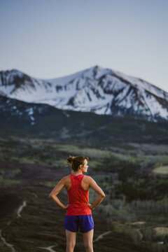 Young woman looks out at the mountains while trail running at dawn