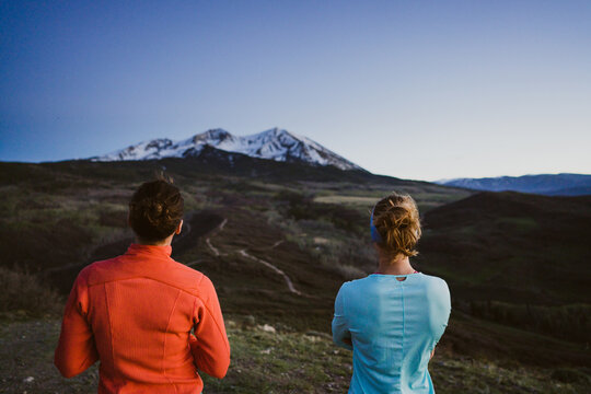 Two female friends look out at a mountain view together at dusk