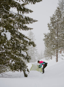 A man in bright jacket stands outside tent in deep snow