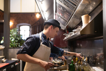 Young man cooking in restaurant kitchen