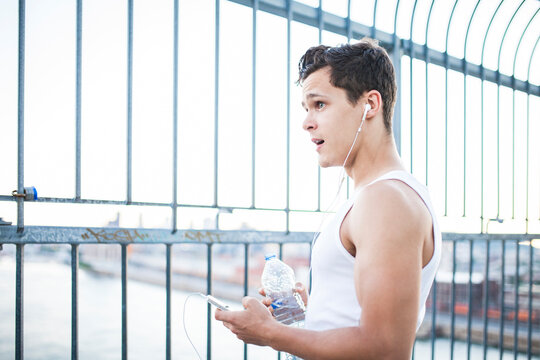 Young man resting after running while drinking water