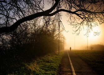 Woman silhouette walking jogging in a foggy morning sunrise in England