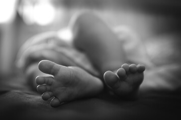 A black and white photo of a newborn feet in the bedroom
