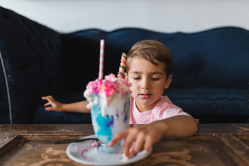 Young boy eating the candy off of a colorful milk shake.