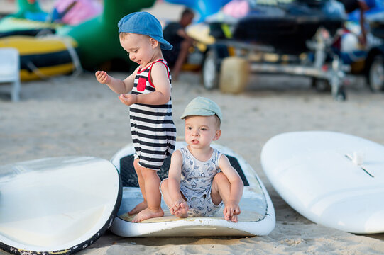 Twin brothers in summer outfit playing on a board in windsurfing camp