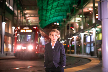Boy wearing suit standing at train station in Downtown.