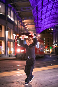 Boy dancing at a Downtown train station at nigh time.