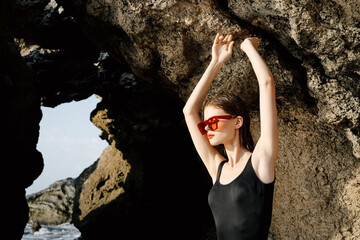 woman in black swimsuit posing near rocks ocean exotic