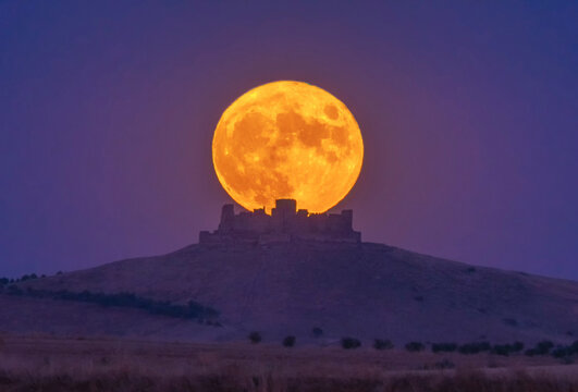 Night view of ancient castle on a mountain with full moon, Spain