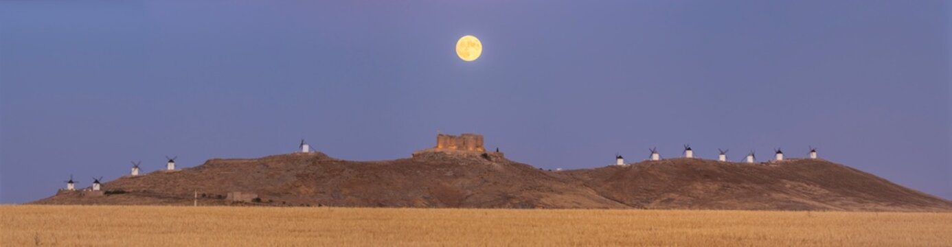 Panoramic view of old castle and windmills with full moon , Spain