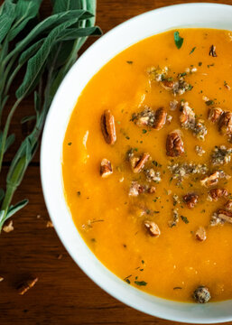 butternut squash soup with pecans and sage in a white ceramic bowl