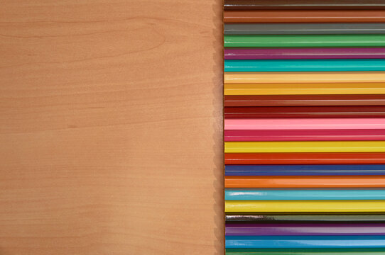 Row Of Colored Pencils On A Wooden Background.