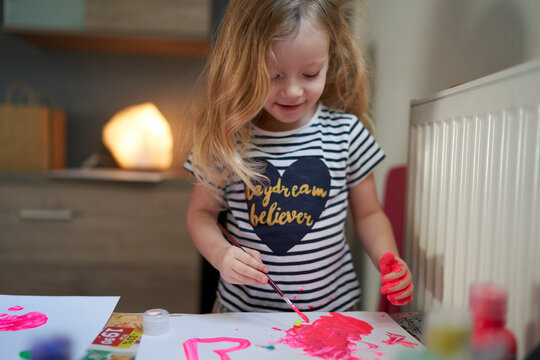 Cute little girl being creative with paint on her hands