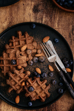 homemade chocolate waffles with blueberries on a dark wooden bac