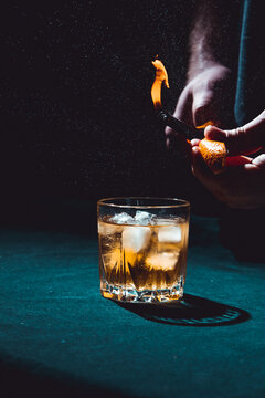 Front angle close up view of a glass of whiskey with flamed orange oil