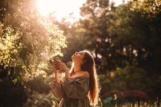 Teenage girl looking up while standing by flowering tree in park