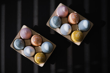 High angle of colorful Easter eggs in egg carton on black background