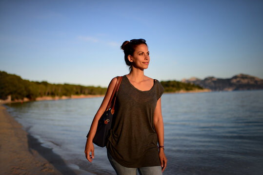 Contemplative young woman walks on the beach