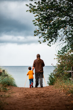 a father and son walking together down a path to the beach