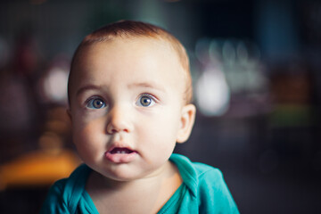 Baby with hazel eyes and green onesie.