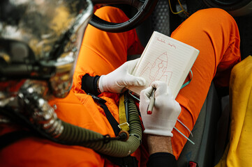 Man dressed as an astronaut draws a rocket on the notebook