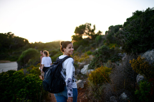 Happy young woman hikes with friends in Mallorca