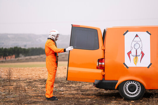 Man dressed as an astronaut opening the door of the van