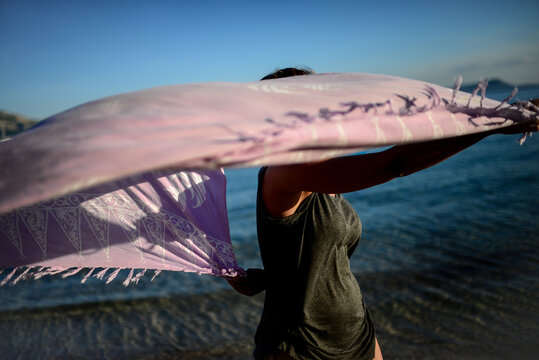 Young woman dances on the beach with sarong