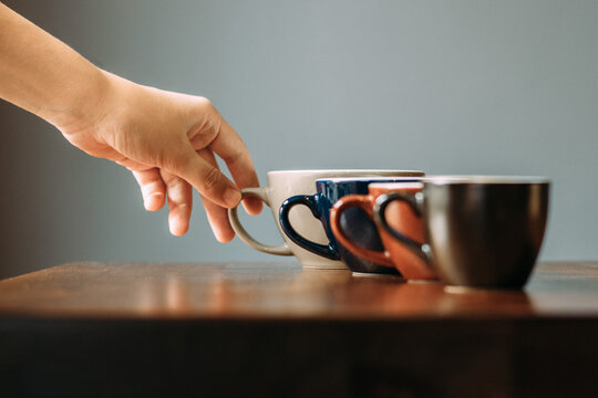 Coffee cups in a row with a hand reaching for them