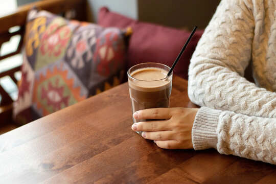Hands of a woman who is sitting in a cafe with a a glass of cocoa