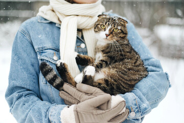 Woman holding a cat in snow