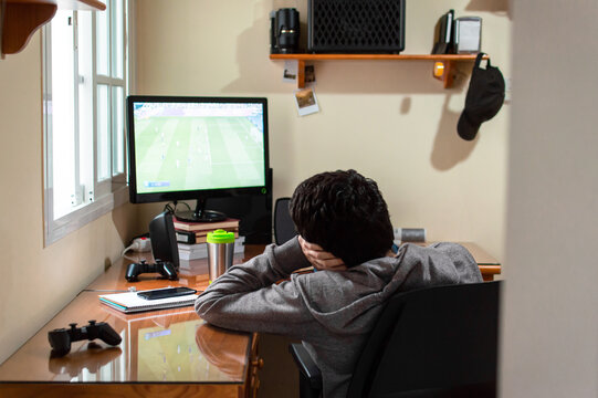 Bored man sitting in his room watching a soccer match on television.
