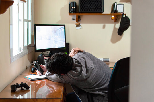 Bored man using a phone in a room full of technology during a long day