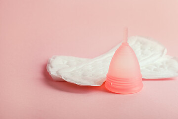 Menstrual cup and sanitary pads isolated on pink background, menstruation cycle products
