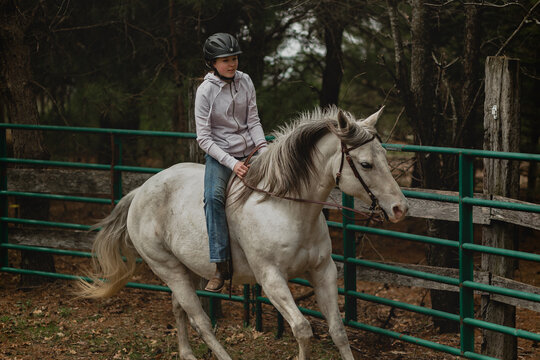 Teen girl loping grey mare bareback in round pen