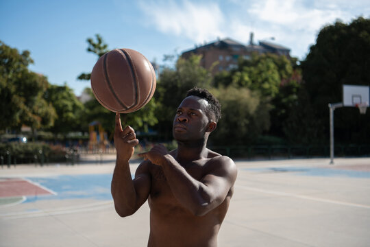 African American athlete doing trick on basketball court