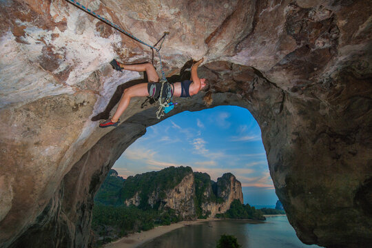 young woman climbing overhanging rock face at Tonsai beach