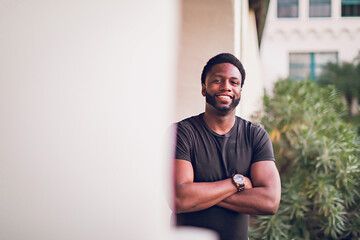 Headshot of a smiling young black man with arms crossed.