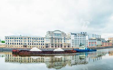 A barge floats on the Moskva River against the background of the Raushskaya Embankment