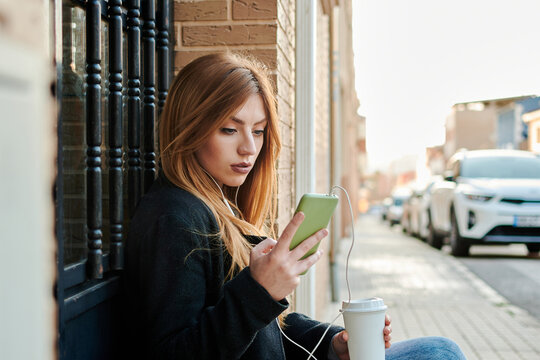 A blonde business woman is drinking coffee and looking at her phone